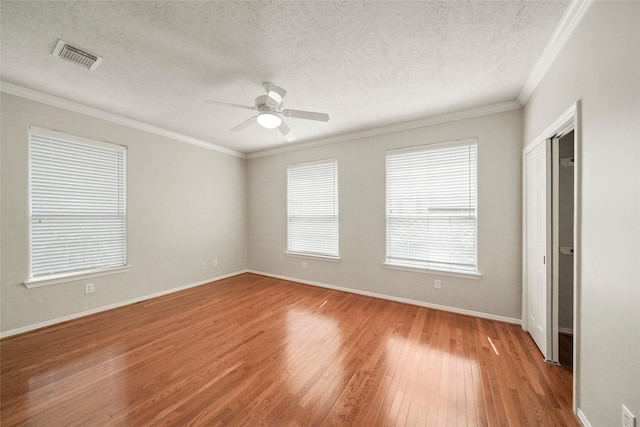 spare room with a textured ceiling, hardwood / wood-style flooring, ceiling fan, and ornamental molding