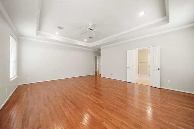 spare room featuring ceiling fan, ornamental molding, light hardwood / wood-style flooring, and a tray ceiling