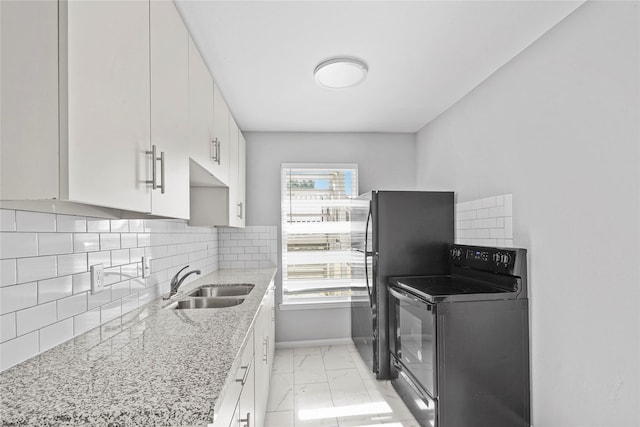 kitchen with electric stove, light stone counters, sink, and white cabinets