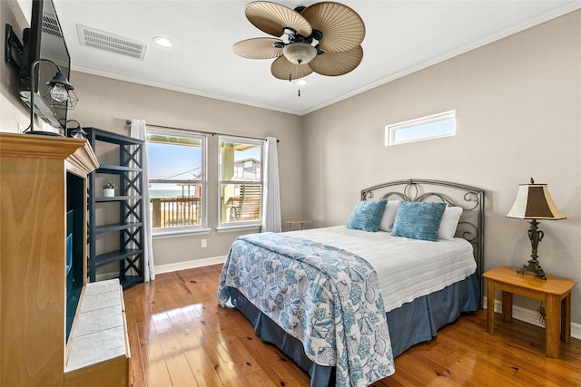 bedroom featuring multiple windows, wood-type flooring, ceiling fan, and crown molding