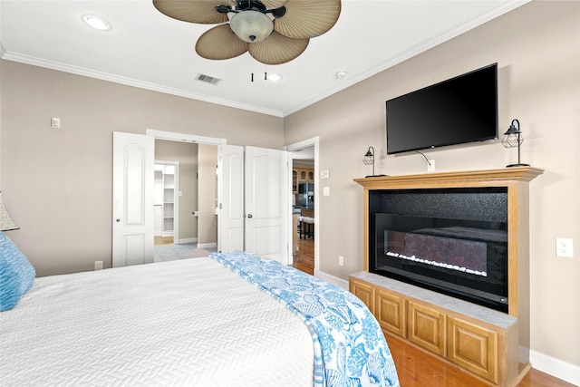 bedroom featuring a closet, a spacious closet, ceiling fan, and crown molding