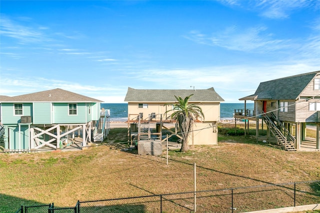 back of property with a water view and a lawn