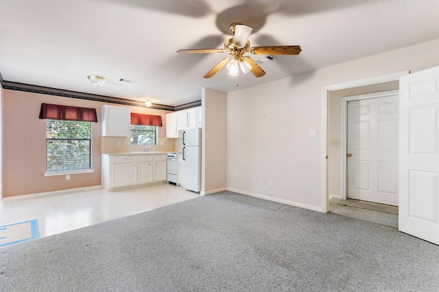 unfurnished living room with light carpet, sink, ornamental molding, and ceiling fan