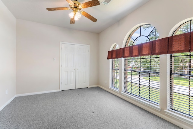 unfurnished bedroom featuring multiple windows, a closet, ceiling fan, and carpet flooring