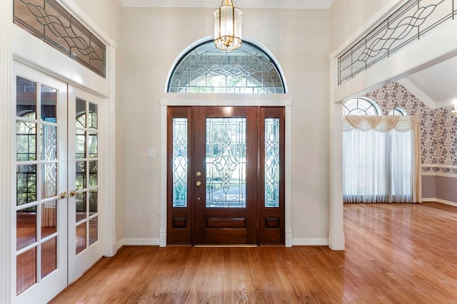 entryway featuring french doors, vaulted ceiling, hardwood / wood-style floors, and a notable chandelier