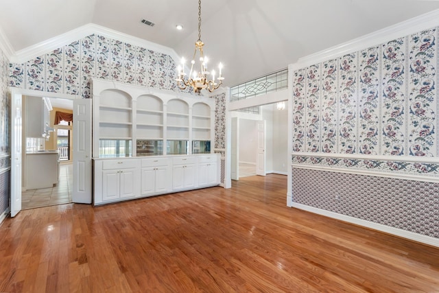 unfurnished dining area featuring crown molding, hardwood / wood-style floors, built in features, and a notable chandelier