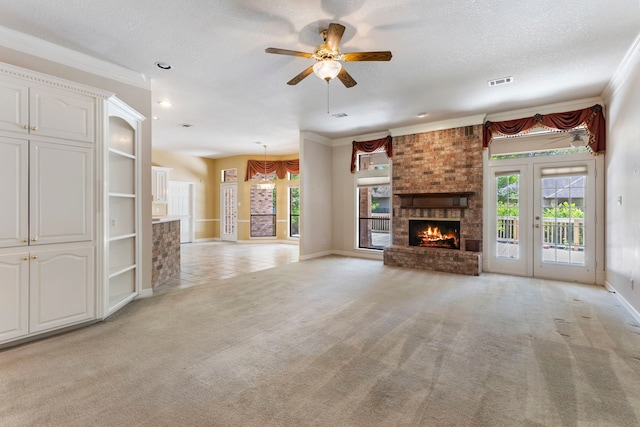 unfurnished living room with a brick fireplace, light carpet, a textured ceiling, ornamental molding, and ceiling fan