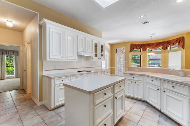 kitchen featuring light tile patterned flooring, a kitchen island, pendant lighting, sink, and backsplash