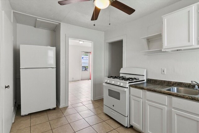 kitchen featuring dark countertops, white appliances, white cabinetry, and a sink