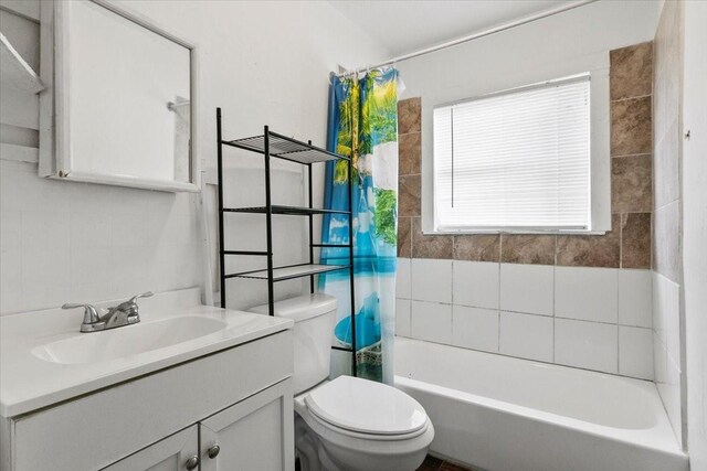 bathroom featuring toilet, tile walls, shower / bath combination with curtain, and vanity