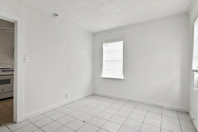 empty room featuring light tile patterned floors, baseboards, and a textured ceiling