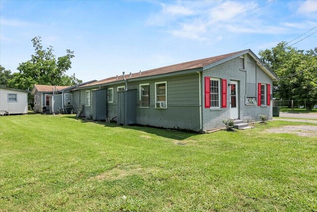 view of side of home with entry steps, brick siding, cooling unit, and a yard