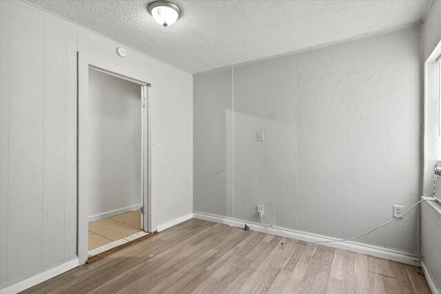 spare room featuring light wood-type flooring and a textured ceiling