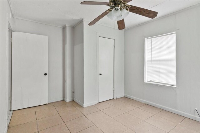 unfurnished bedroom with crown molding, multiple windows, light tile patterned flooring, and baseboards