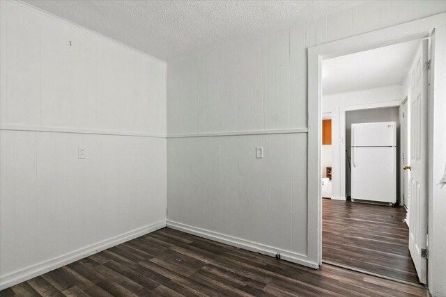 spare room with dark wood-style floors, a textured ceiling, and baseboards