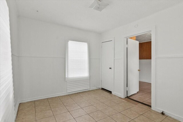 spare room featuring light tile patterned floors and a textured ceiling