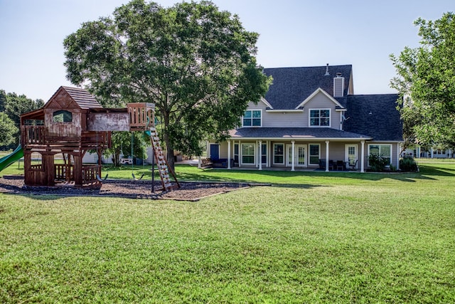 rear view of property featuring a yard and a playground