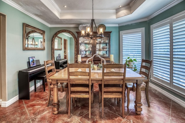 dining area with crown molding, a notable chandelier, and a tray ceiling