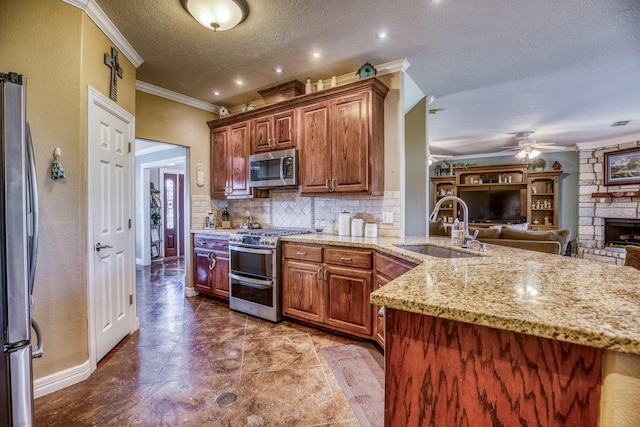 kitchen with appliances with stainless steel finishes, sink, light stone countertops, a textured ceiling, and decorative backsplash