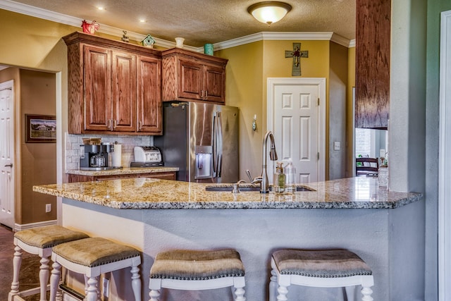 kitchen featuring sink, tasteful backsplash, stainless steel fridge with ice dispenser, light stone counters, and ornamental molding