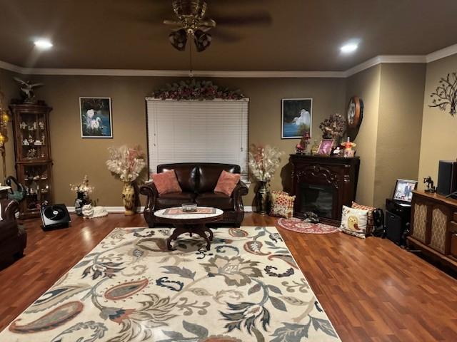 living room featuring ornamental molding, a fireplace, wood finished floors, and baseboards