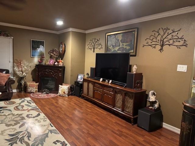 living area with baseboards, a fireplace, ornamental molding, and wood finished floors