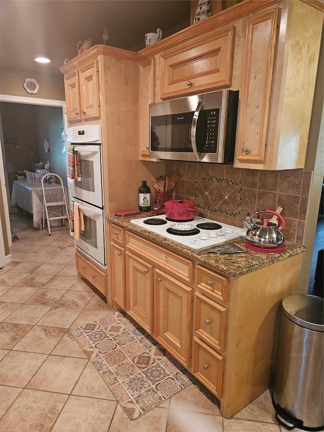 kitchen with tasteful backsplash, stone countertops, white appliances, and light tile patterned floors