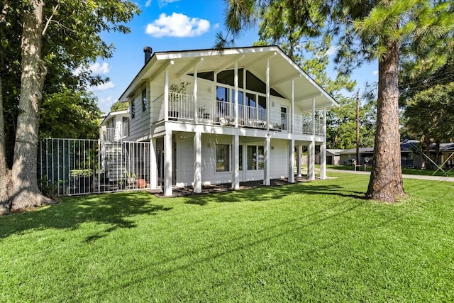 back of house featuring a balcony and a yard