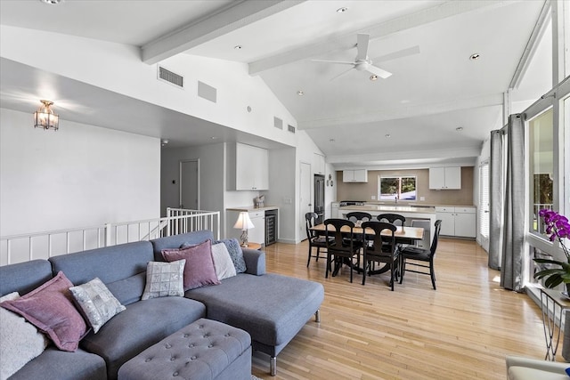 living room featuring lofted ceiling with beams, ceiling fan, wine cooler, and light hardwood / wood-style flooring