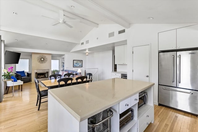 kitchen featuring vaulted ceiling with beams, a kitchen island, light hardwood / wood-style floors, white cabinetry, and stainless steel appliances