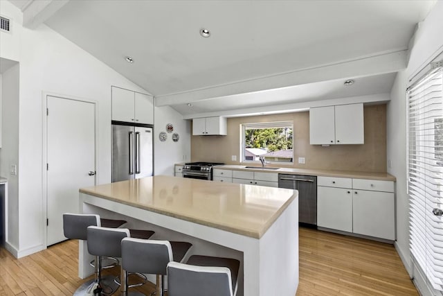 kitchen featuring vaulted ceiling with beams, light wood-type flooring, white cabinetry, and stainless steel appliances