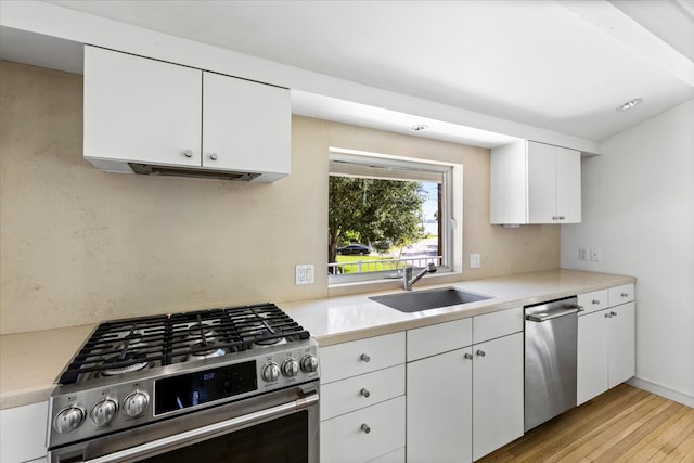 kitchen featuring white cabinetry, sink, stainless steel appliances, and light hardwood / wood-style flooring