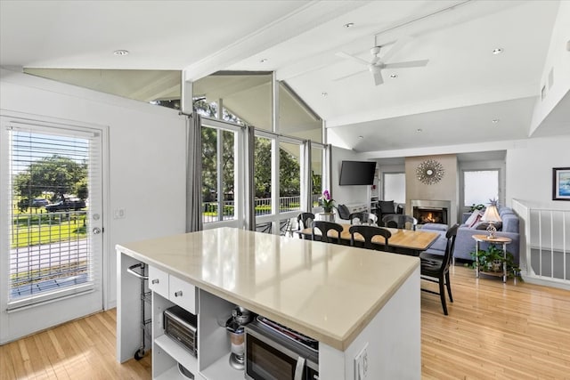 kitchen with white cabinets, lofted ceiling with beams, ceiling fan, and light wood-type flooring