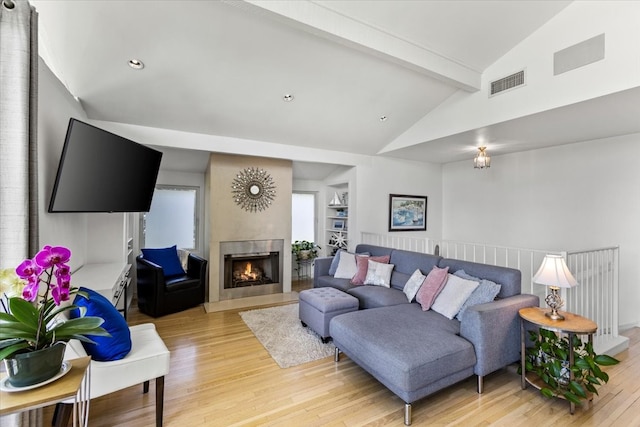 living room with vaulted ceiling with beams, light hardwood / wood-style floors, and built in features