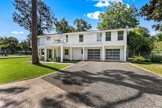 view of front of house featuring a garage, a balcony, and a front lawn