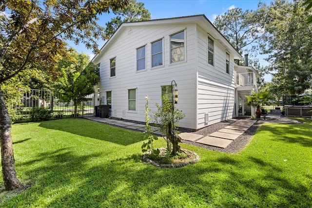 back of house featuring a lawn and a balcony