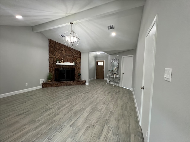 unfurnished living room with a fireplace, vaulted ceiling with beams, light hardwood / wood-style floors, and an inviting chandelier