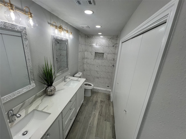 bathroom with vanity, a tile shower, hardwood / wood-style floors, and toilet