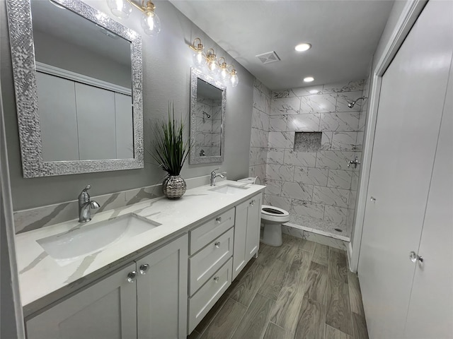 bathroom featuring tiled shower, hardwood / wood-style flooring, toilet, and vanity