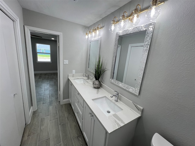 bathroom with toilet, vanity, and wood-type flooring