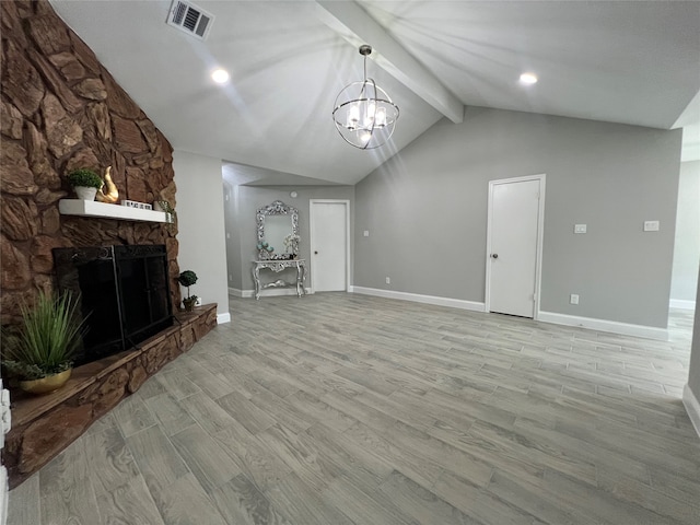 unfurnished living room featuring light wood-type flooring, vaulted ceiling with beams, a stone fireplace, and an inviting chandelier