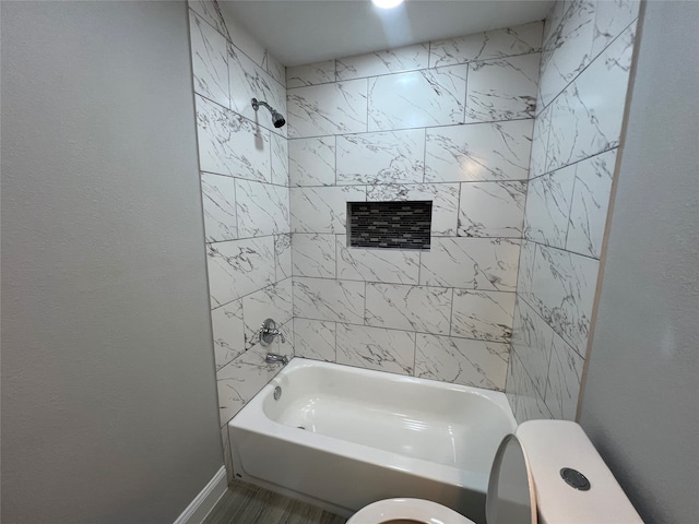 bathroom featuring tiled shower / bath combo and toilet