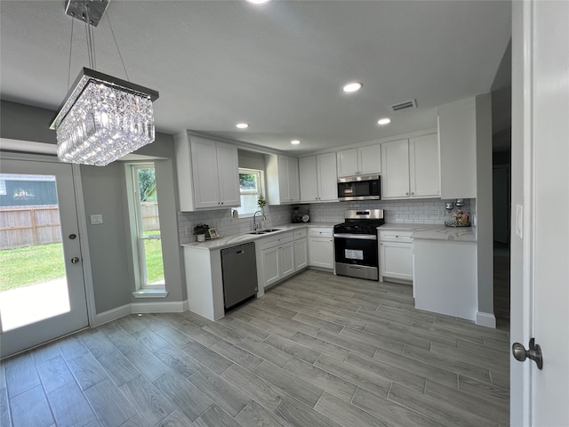 kitchen with sink, stainless steel appliances, tasteful backsplash, and white cabinets