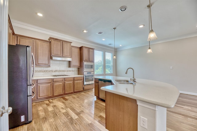 kitchen featuring appliances with stainless steel finishes, sink, light hardwood / wood-style flooring, hanging light fixtures, and an island with sink