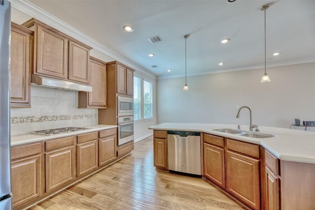 kitchen featuring decorative light fixtures, sink, appliances with stainless steel finishes, and light hardwood / wood-style flooring