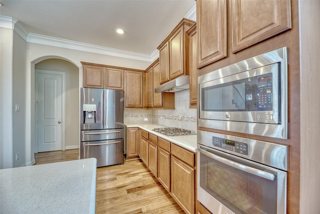 kitchen with decorative backsplash, appliances with stainless steel finishes, light wood-type flooring, and crown molding