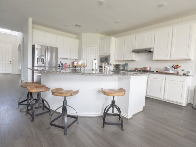 kitchen featuring appliances with stainless steel finishes, dark wood-type flooring, an island with sink, and white cabinetry