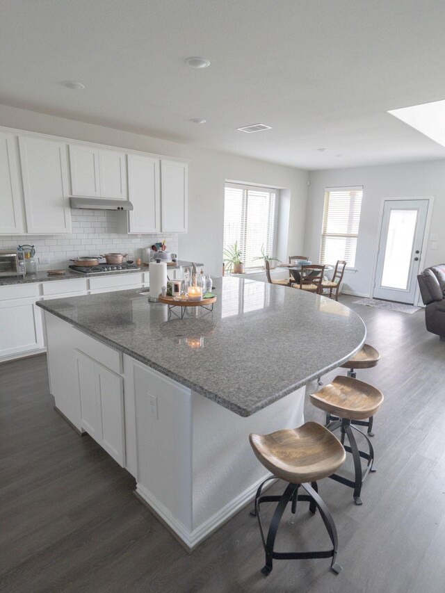 kitchen with white cabinets, dark stone counters, backsplash, and dark hardwood / wood-style floors