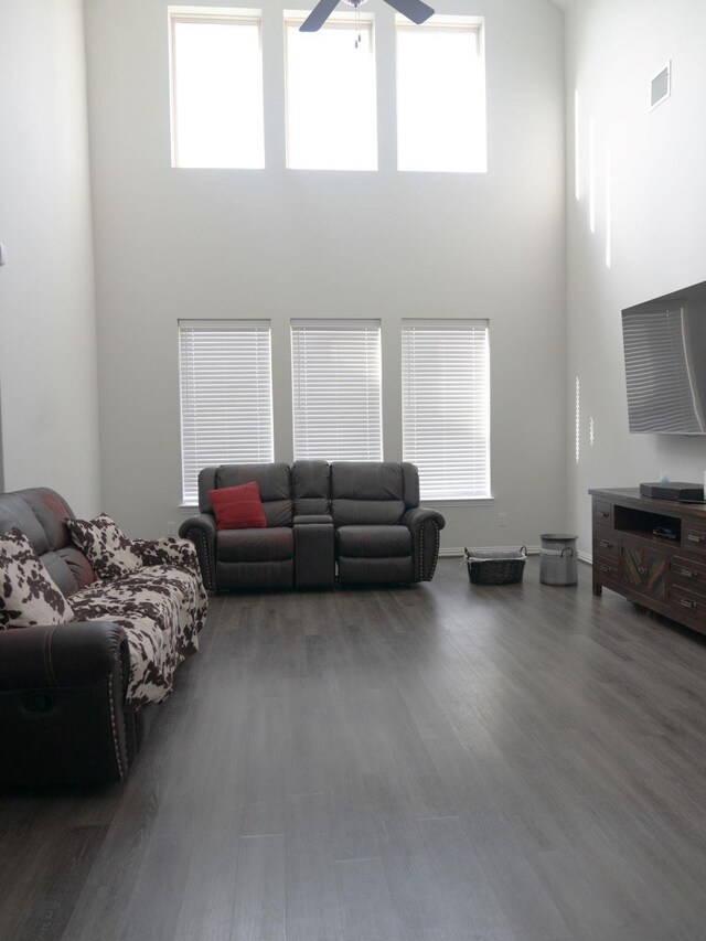 living room featuring a towering ceiling, wood-type flooring, and ceiling fan