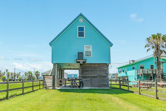 rear view of house featuring a lawn and a fenced backyard